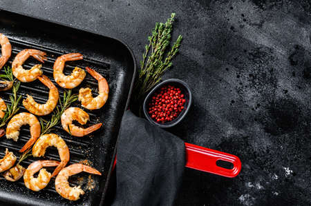 Fried king prawns, shrimps in a pan. Black background. Top view. Copy space.