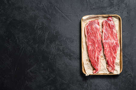 Raw flank steak. Fillet of marbled beef. Black background. Top view. Space for text.