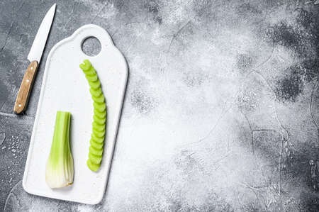 Fresh sliced celery on a white chopping Board. Gray background. Top view. Space for text.
