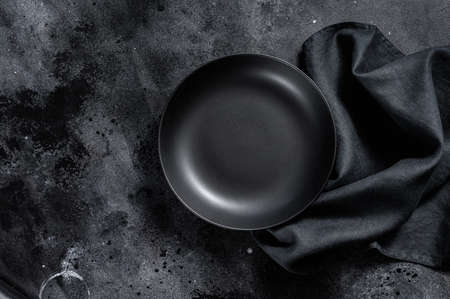Black plate and a towel on textured black background. Top view. Copy space.の写真素材