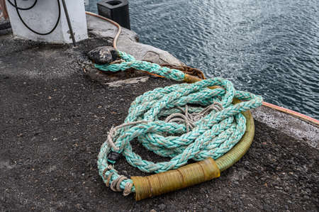 Old rusted mooring bollard with knotted nautical ropes. Selective focus. Los Gigantes, Tenerife.の写真素材