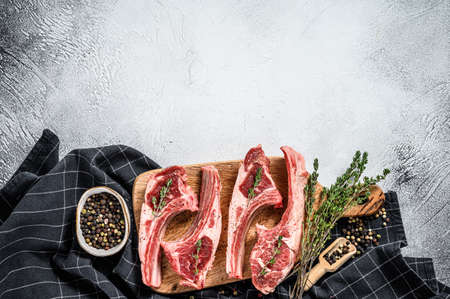 Raw fresh lamb ribs with pepper and thyme. Organic meat. White background. Top view. Copy space.