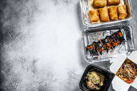 Different containers with delicious food. Delivery service. Asian cuisine, dumplings, spring rolls, dim sum, Peking duck. White background. Top view. Copy space.の写真素材