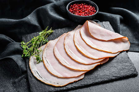 Slices of pork ham with thyme. Organic meat. Black background. Top view