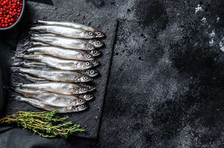 Raw small fish anchovies with pepper and thyme. Black background. Top view. Copy space.の写真素材