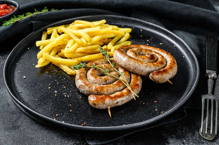 Spiral grilled sausages with a side dish of French fries. Black background. Top view.の写真素材