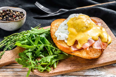 Brioche sandwich with bacon, egg Benedict and hollandaise sauce. White background. Top view.