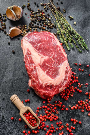 Raw fresh meat Ribeye Steak with seasoning. Rib eye beef steak. black background. top view.の写真素材