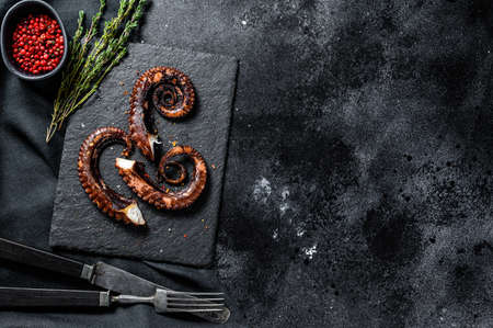 Fried octopus tentacles with thyme and pink pepper. Fresh seafood. Black background. Top view. Copy space.の写真素材