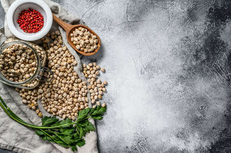 Chickpeas in a glass jar with parsley and pink pepper. Healthy vegetarian food. Gray background. Top view. Space for textの写真素材