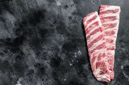Fresh raw pork spare ribs. Black background. Top view. Copy space.