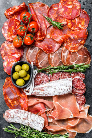 Cured meat platter of traditional Spanish tapas. Chorizo, jamon serrano, lomo and fuet. Black background. Top view.の写真素材