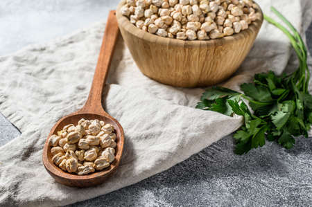 Chickpeas in a wooden spoon. Healthy vegetarian food. Gray background. Top view.の写真素材