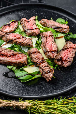 Steak salad with spinach, arugula and sliced beef marbled steak. Black background. Top view.の写真素材