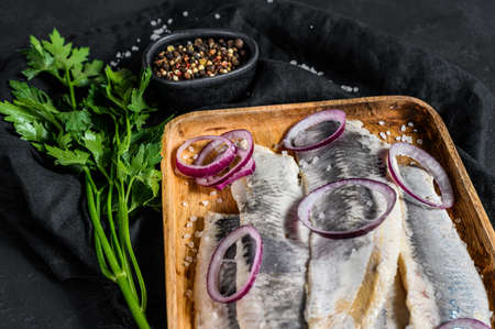 Marinated herring fillet with pepper, herbs and red onion. Black background. Top view.の写真素材