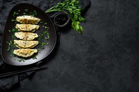 Plate of fried Korean dumplings on rustic black table. Top view. Space for text.の写真素材