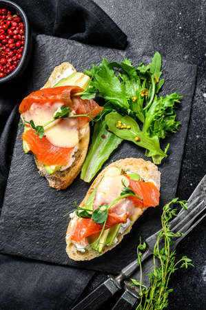Toasts with avocado and smoked salmon. Black background. Top view.の写真素材