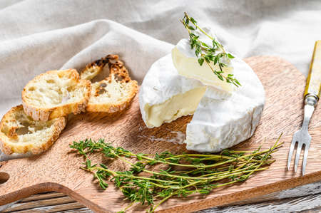 French Camembert cheese with grapes on wooden cutting board. White background. Top view.の写真素材