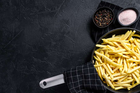 French fries in a frying pan. Black background. Top view. Space for text.の写真素材