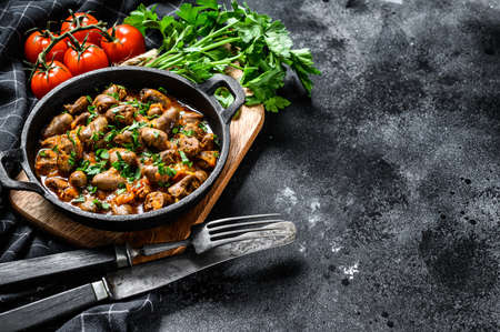 Stew with chicken hearts and vegetables with fresh parsley. Black background. Top view. Copy space.の写真素材