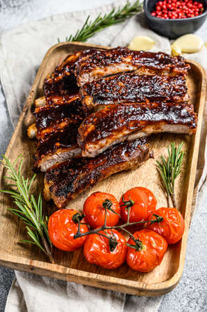 Delicious barbecued ribs seasoned with a spicy basting sauce and served with baked tomatoes. Gray background. Top view.の写真素材