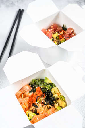 Wok noodle in paper box with vegetables , salmon and tuna. street food to go, take away. White...
