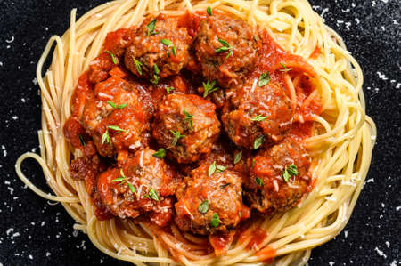 Italian pasta spaghetti with tomato sauce and meatballs. Black background. Top view.の写真素材
