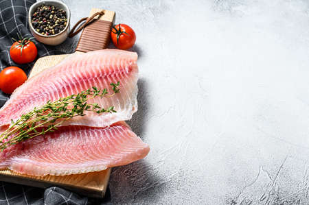 Telapia fillet on a cutting Board with thyme and pink pepper. White background. Top view. Copy space.の写真素材