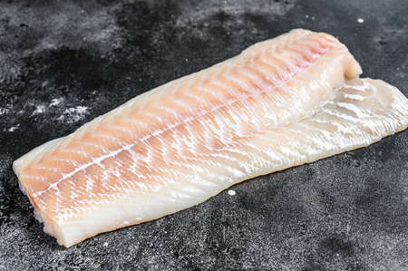 Raw Norwegian skrei cod fish fillet. Black background. Top view.の写真素材