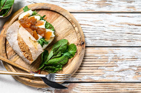 Sandwich with goat cheese, pear marmalade, chard and spinach on Baguette bread. White wooden background. Top view. Copy space.の写真素材