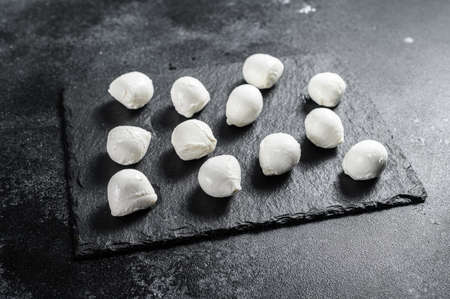 Mini mozzarella cheese balls on a stone Board. black background. Top view.