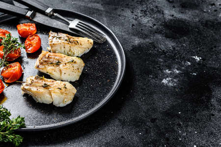 A portion of Grilled, baked pollock or coalfish fillets. Black background. Top view. Copy space.の写真素材