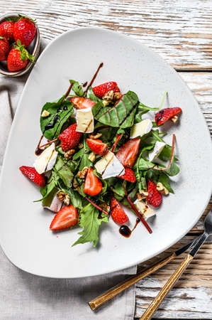 Diet salad with brie cheese, strawberries, nuts, chard and arugula. White background. Top view.の写真素材