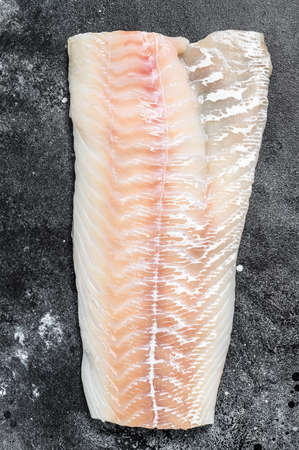 Raw Norwegian skrei cod fish fillet. Black background. Top view.の写真素材