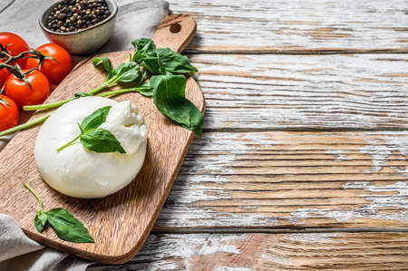 Italian Burrata buffalo cheese with Basil leaves. White wooden background. Top view. Copy space.の写真素材