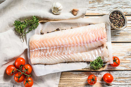 Fresh Raw Cod loin fillet with thyme. White wooden background. Top view.