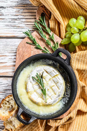 Baked brie cheese, Camembert with rosemary in a pan. White wooden background. Top view.の写真素材