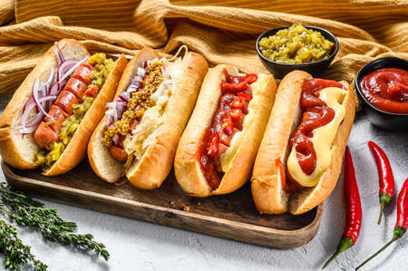 Hot dogs fully loaded with assorted toppings on a tray. Delicious hot-dogs with pork and beef sausages. White background. Top view.の写真素材