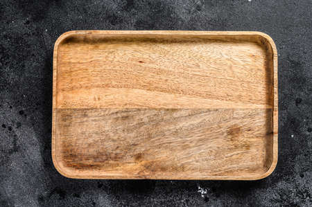 Wooden antique tray. Black texturized background. Top view. Copy space.