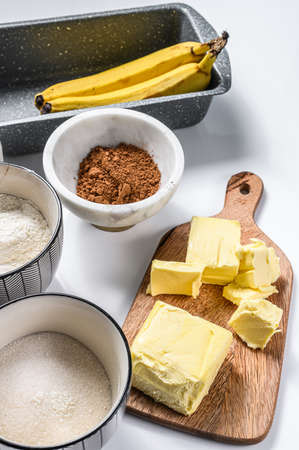 Ingredients for Banana bread recipe. Banana, chocolate, flour, egg, sugar, butter, chocolate. White background. Top view.の写真素材