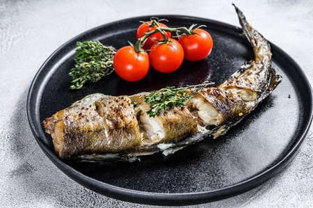 Delicious grilled hake with fresh thyme and tomatoes. Black background. Top view.の写真素材