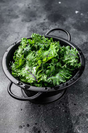 Fresh kale salad in a colander. Vegetarian food. Black background. Top view.の写真素材