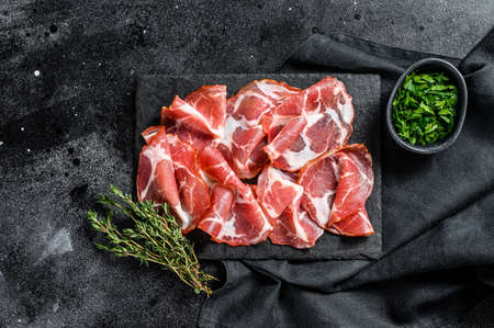 Italian rolled bacon Pancetta Piacentina. Pork meat. Black background. Top view.の写真素材