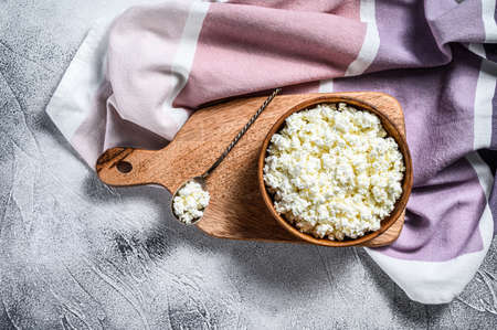 Fresh Cottage cheese in a wooden bowl. Gray background. Top view.の写真素材