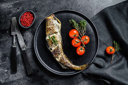 Delicious grilled pollock with fresh thyme and tomatoes. Black background. Top view.の写真素材