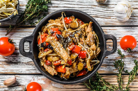 Udon stir fry noodles with chicken and vegetables in a pan. White background. Top view.の写真素材