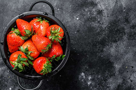 Fresh red strawberries in a colander. Black background. Top view. Copy spaceの写真素材