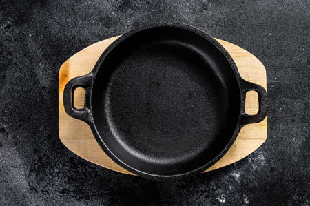 Empty cast iron frying pan on dark background. Top view. Copy space.の写真素材