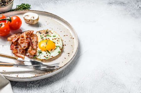 Plate of fried eggs with bacon and fresh tomato, mushroom. Breakfast set. White background. Top view. Copy space.の写真素材