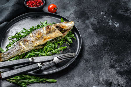 Baked sea Bass fish with arugula, grilled seabass. Black background. Top view. Copy space.の写真素材